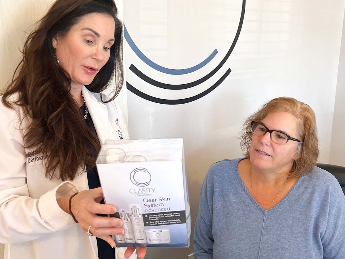 Dermatologist explaining skincare product to client.