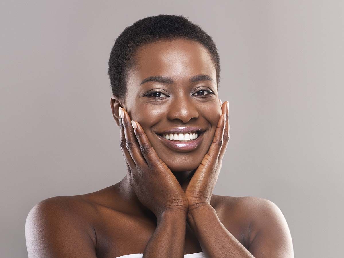 Smiling woman with short hair touching her face