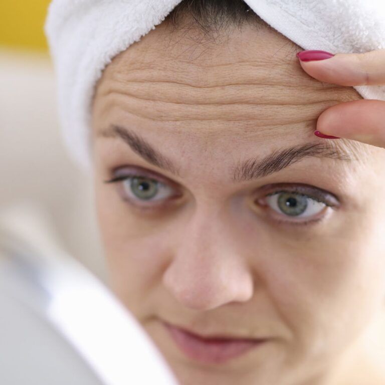Woman examining her face in the mirror.