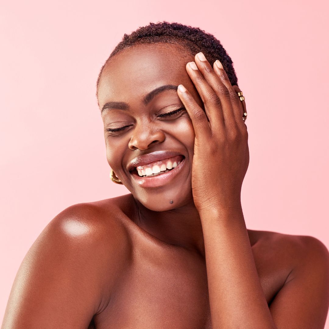 Smiling woman with short hair against pink backdrop.
