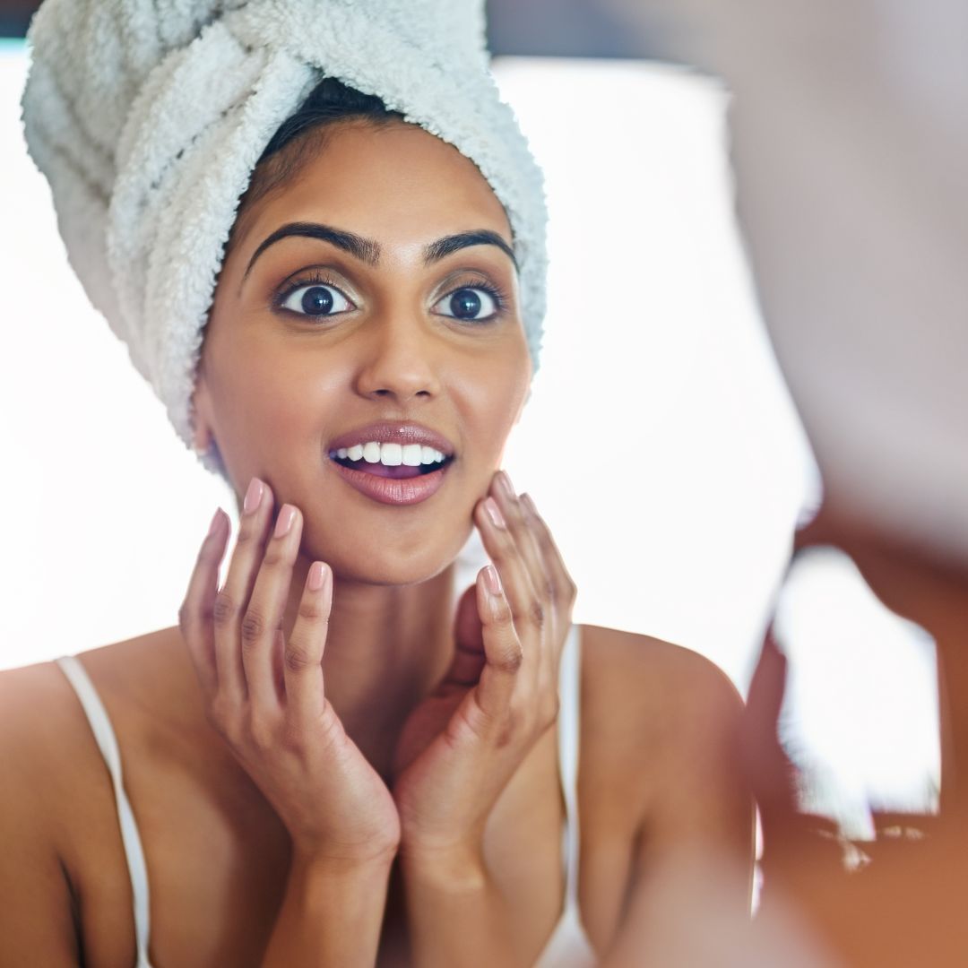 Woman admiring her reflection with surprise and joy.