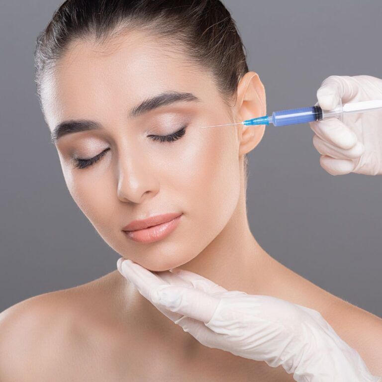 Cosmetic procedure with syringe on woman's face.