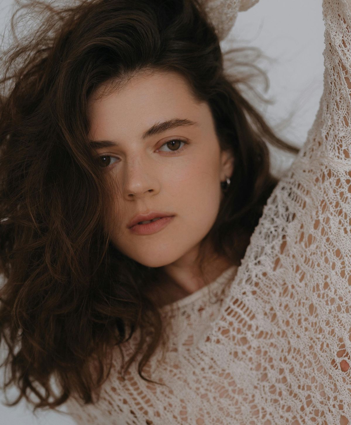 Woman with curly hair in knitted sweater.