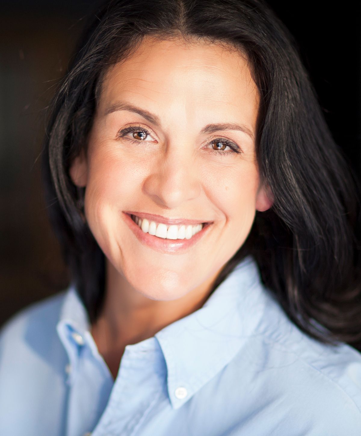 Smiling woman wearing a light blue shirt.