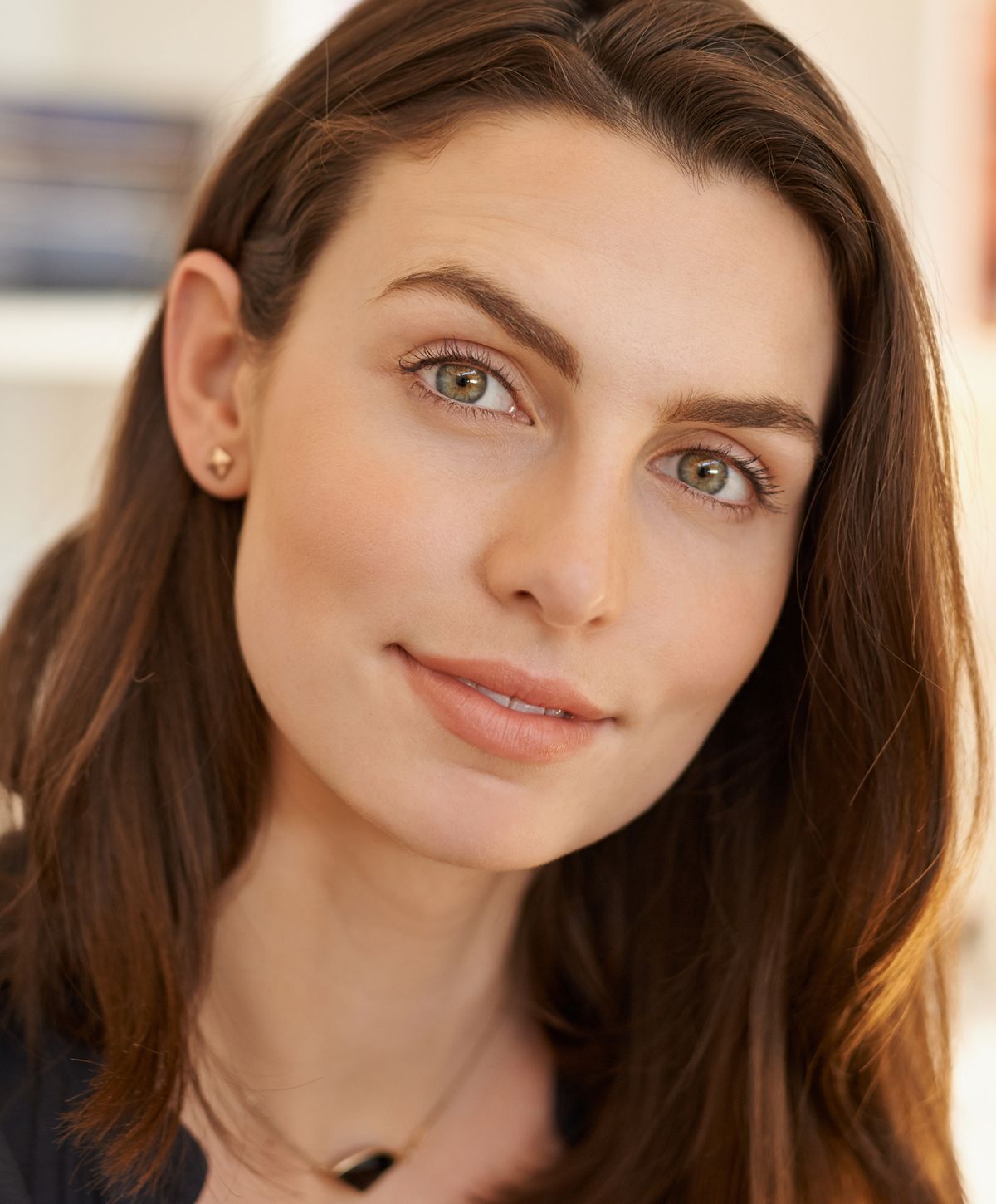 Young woman with long, wavy hair smiling gently.