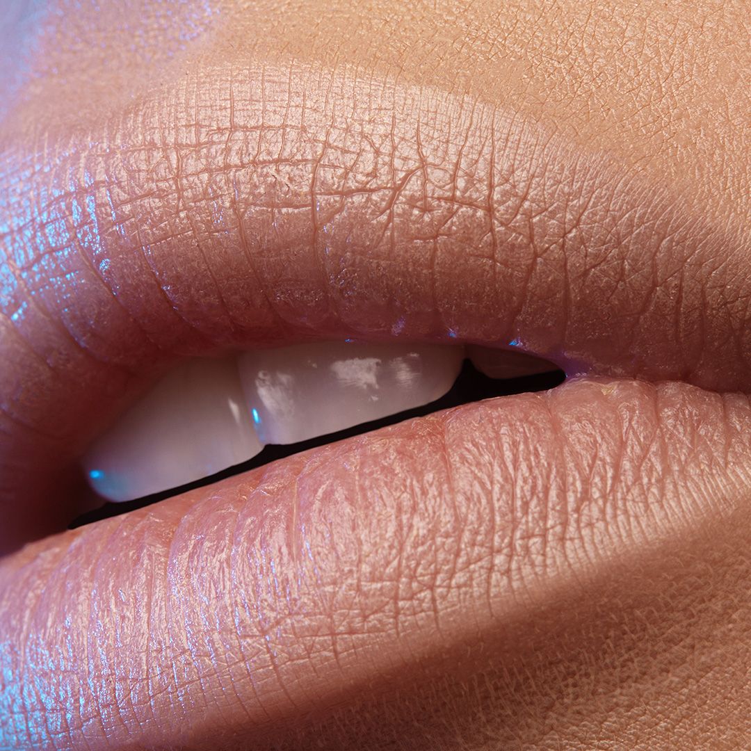 Close-up of smooth, glossy, nude-colored lips.