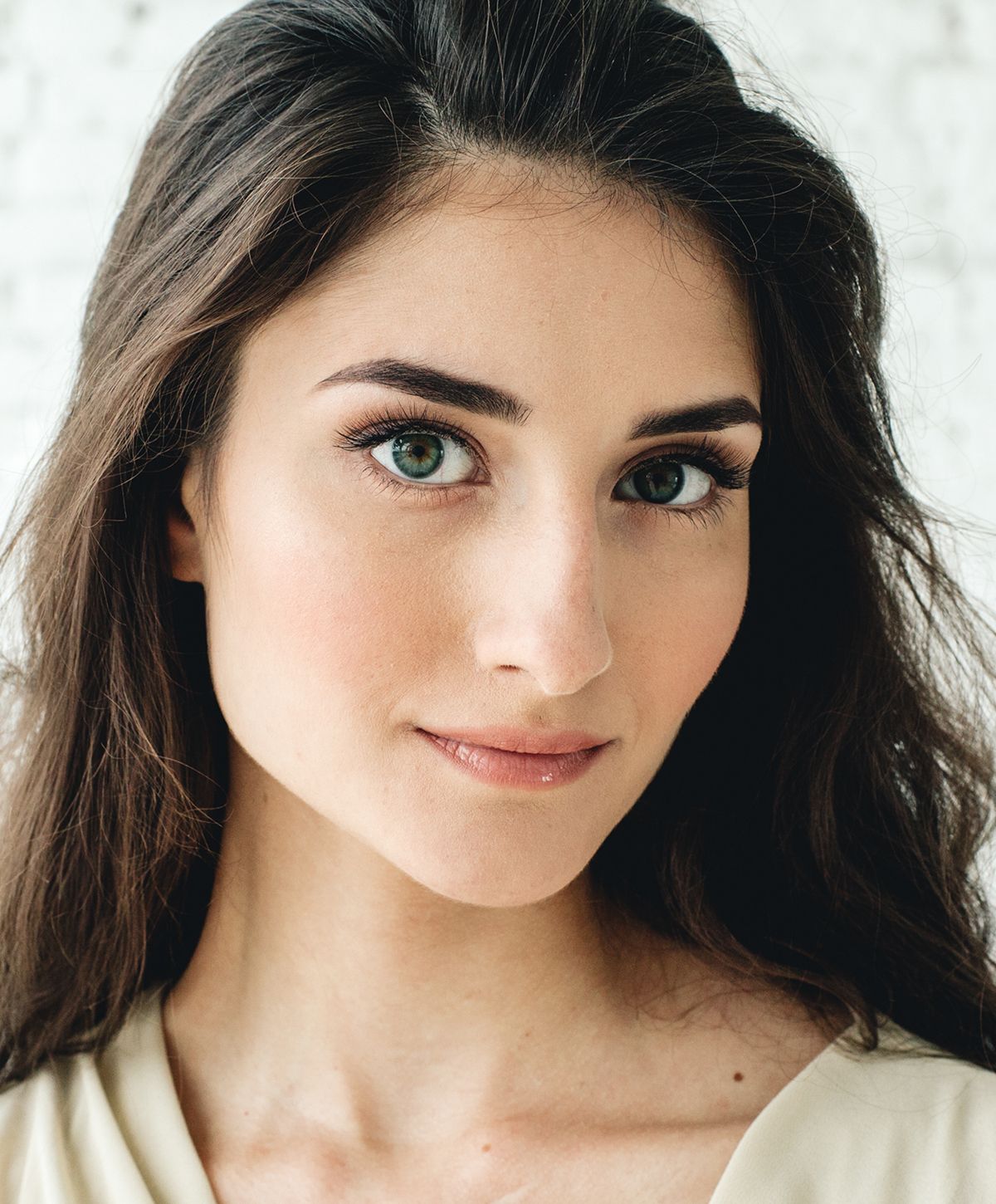 Young woman with long, wavy hair smiling gently.