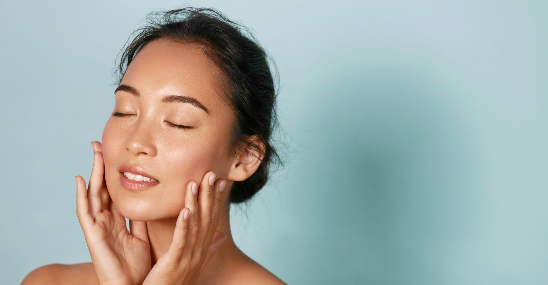 Woman enjoying skincare routine against blue background.
