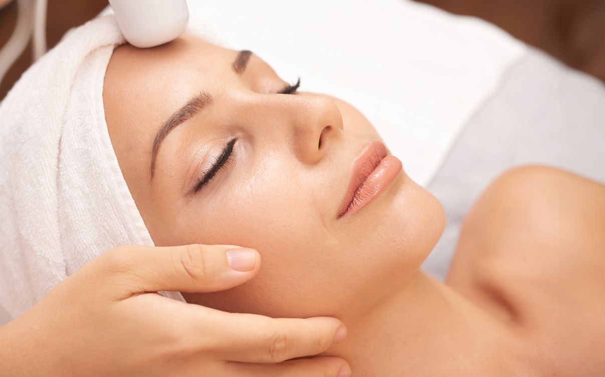 Woman receiving skin treatment with laser device.