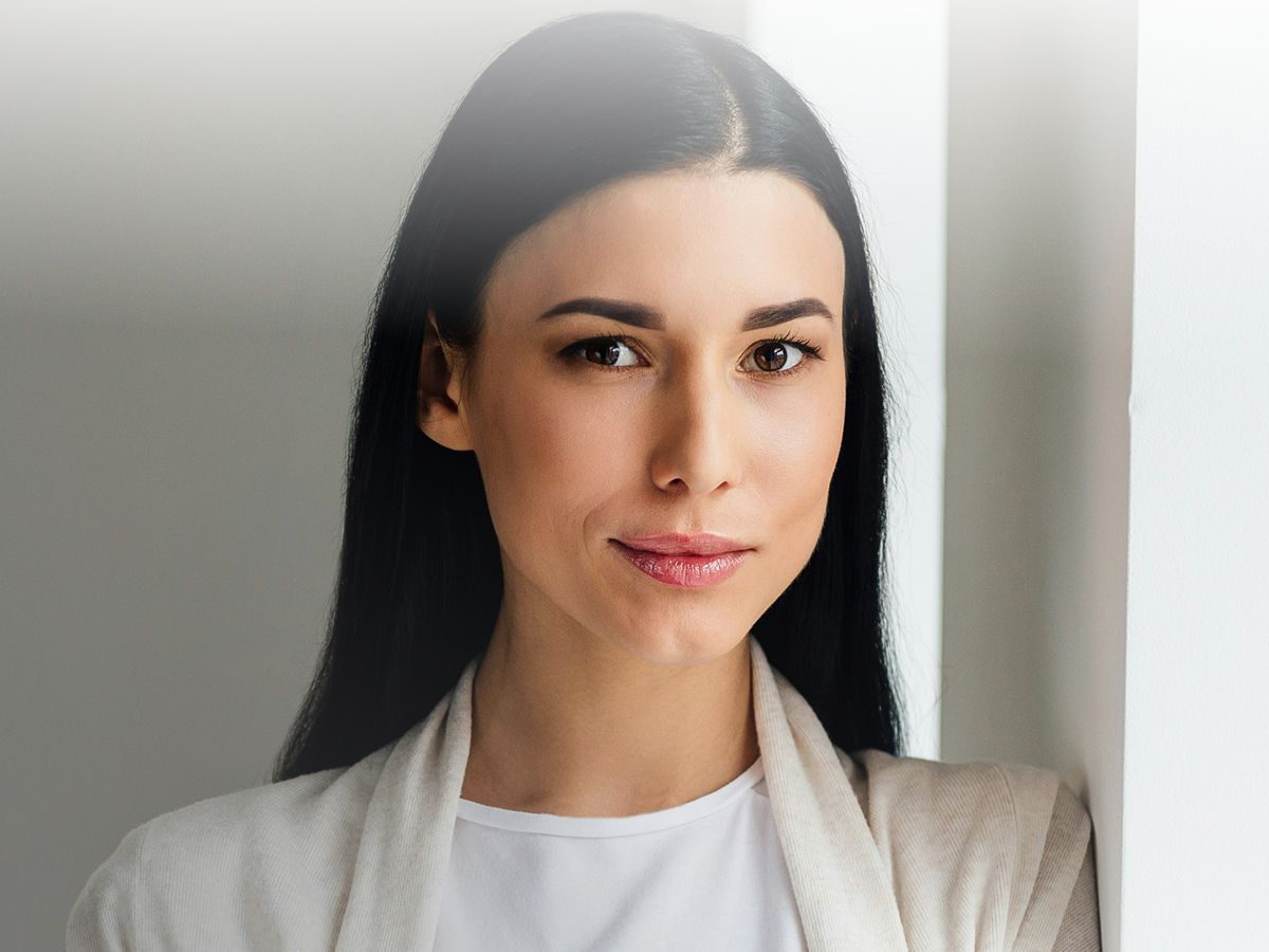 Woman smiling near a white wall.