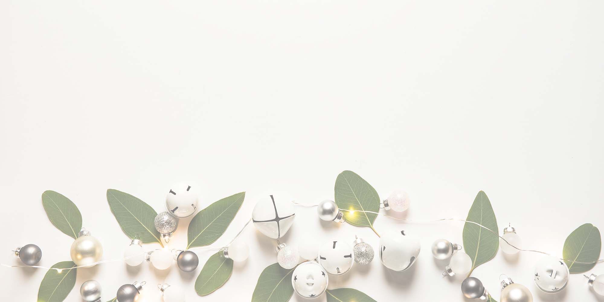 Decorative holiday ornaments and greenery on white background.