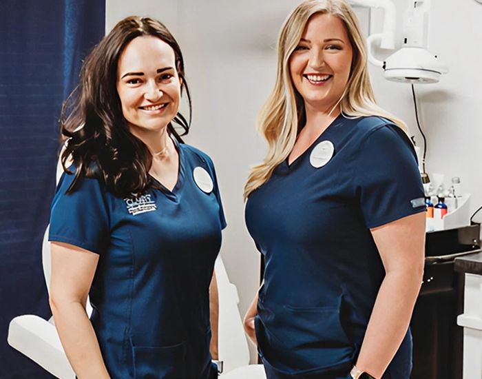 Two healthcare professionals smiling in scrubs.