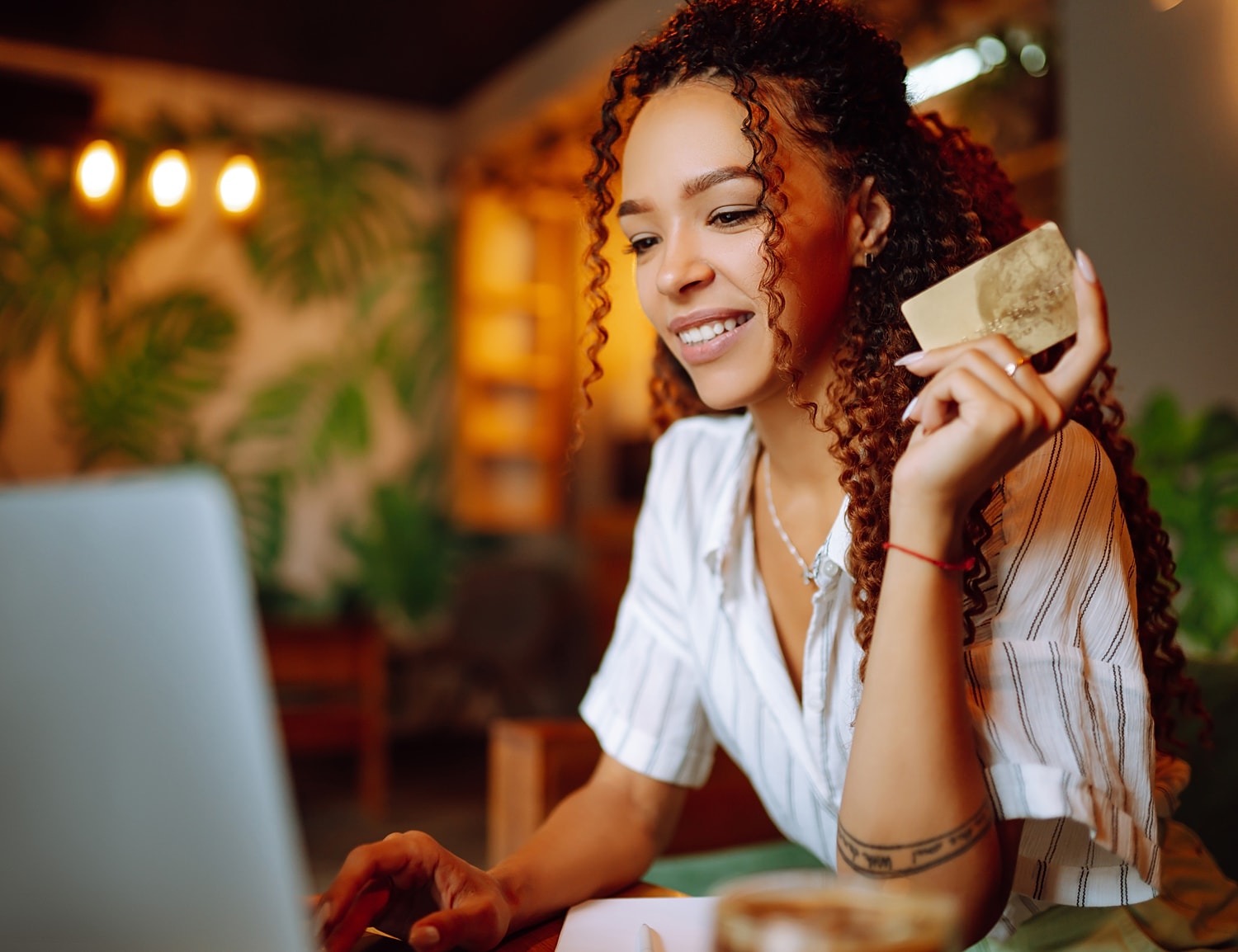 Smiling woman using laptop with credit card.