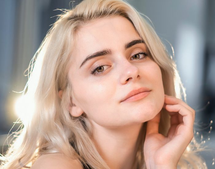 Woman with blonde hair, soft smile, natural lighting.