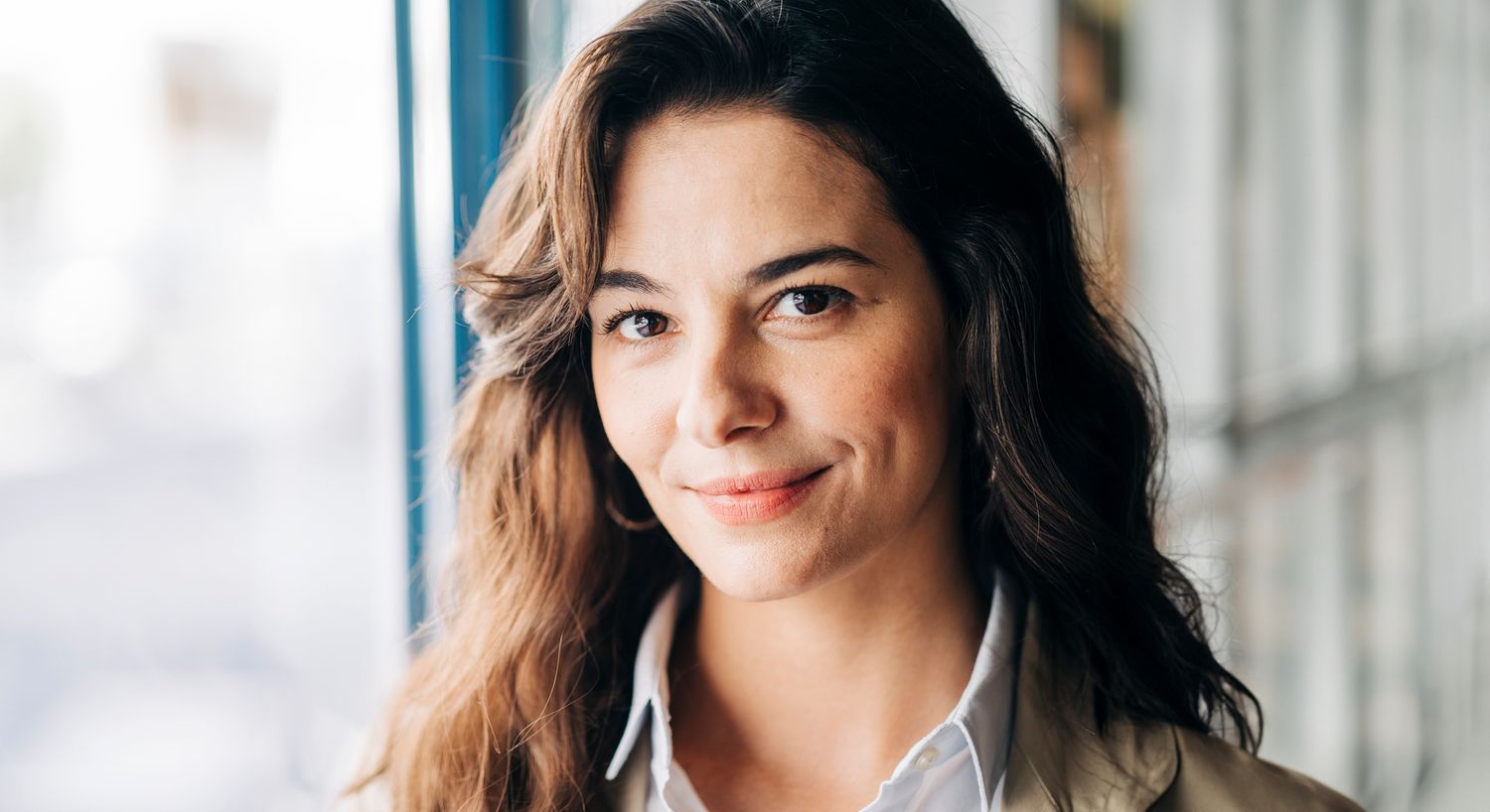 Smiling woman with wavy hair indoors.