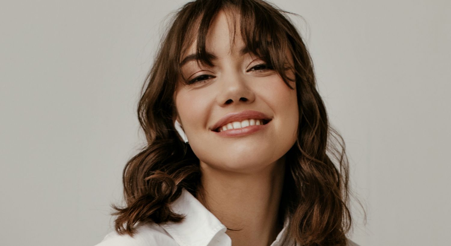 Smiling woman with earbuds in casual attire.